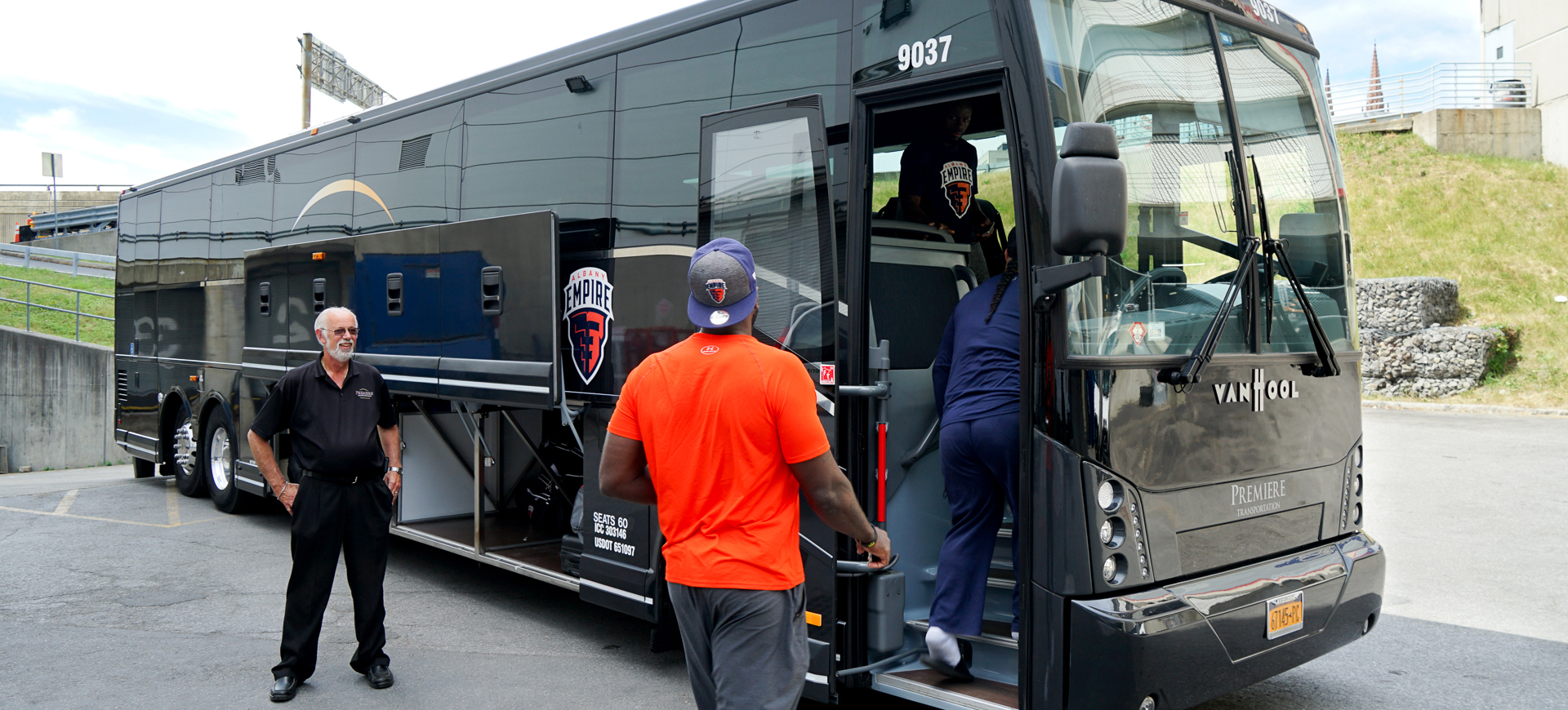 Sports team getting on Premiere bus with driver